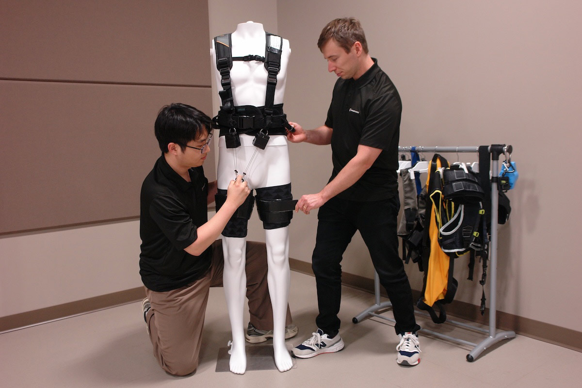 Two Biomechanics students work with an exosuit in a lab