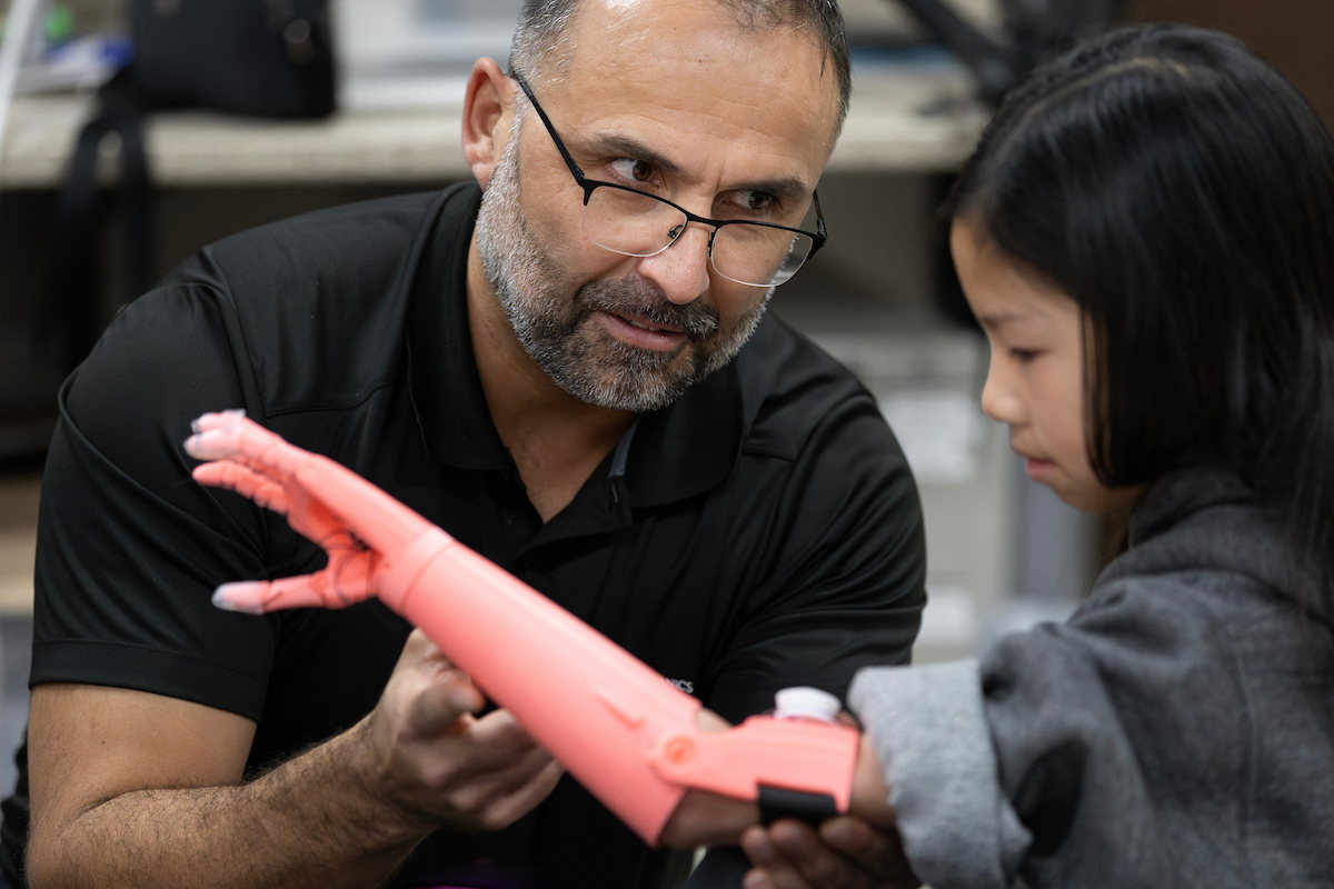 one person works on a pink 3d printed prosthetic for a child