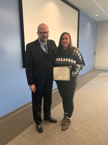 a photo of two people standing next to each other with one person holding an certificate.
