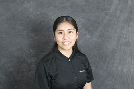 a person with long black hair smiling wearing a black polo.