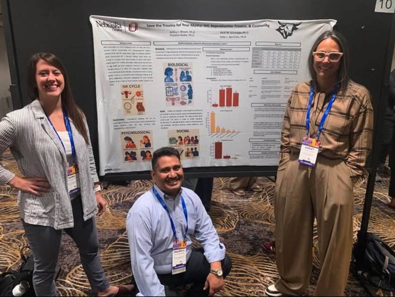 Drs. Schneider, Rudra, and Blount posing in front of their research poster.