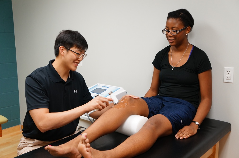 Athletic training student checks a knee injury.