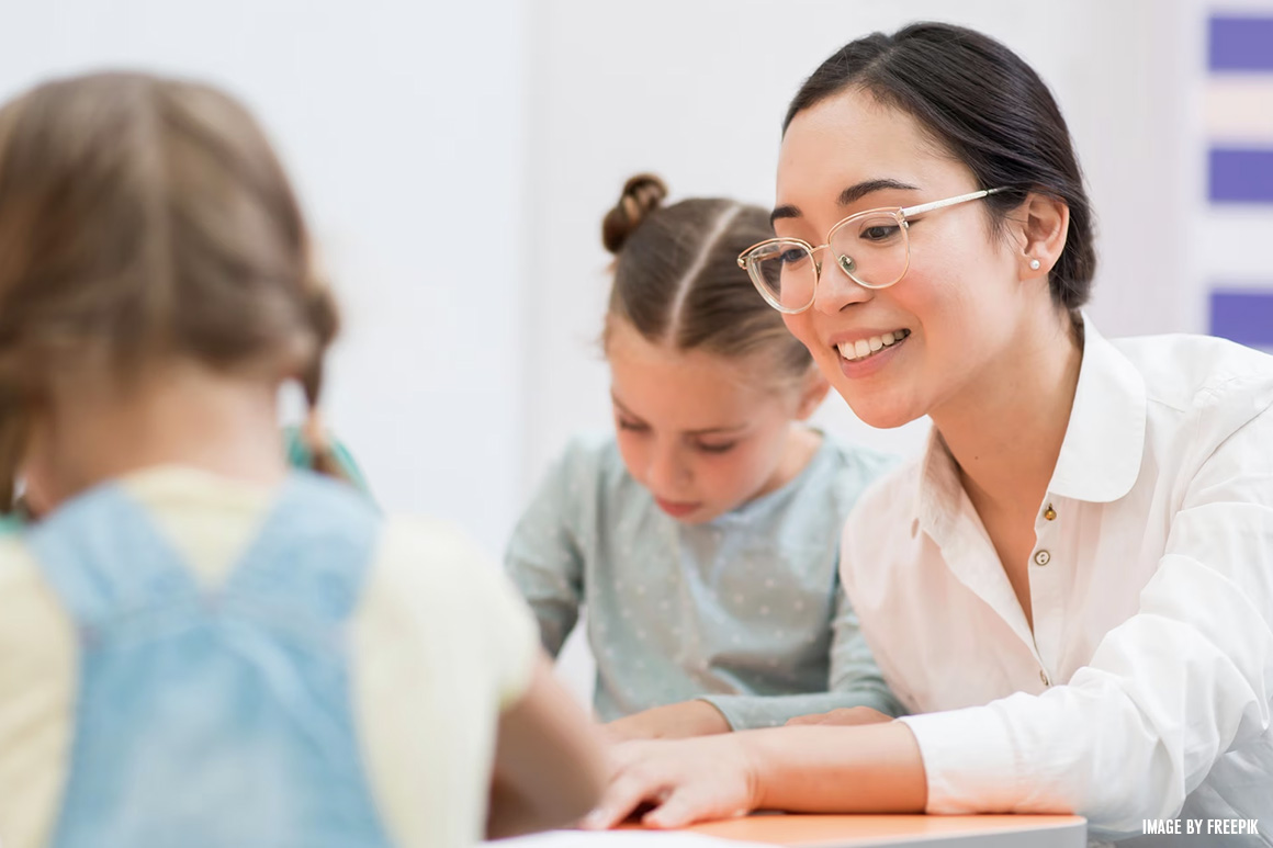 A teacher helps two young students with reading