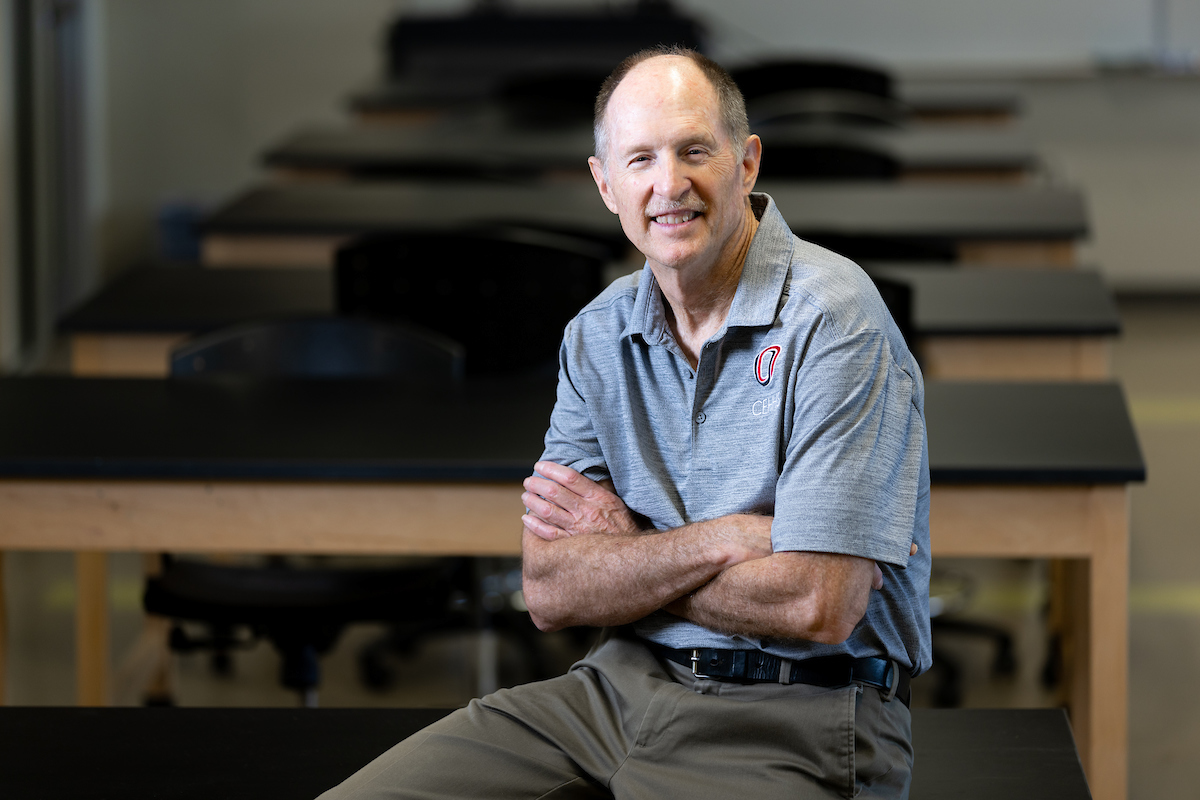 Dr. Neal Grandgenett sits on a lab table in the STEM Room at Roskens Hall