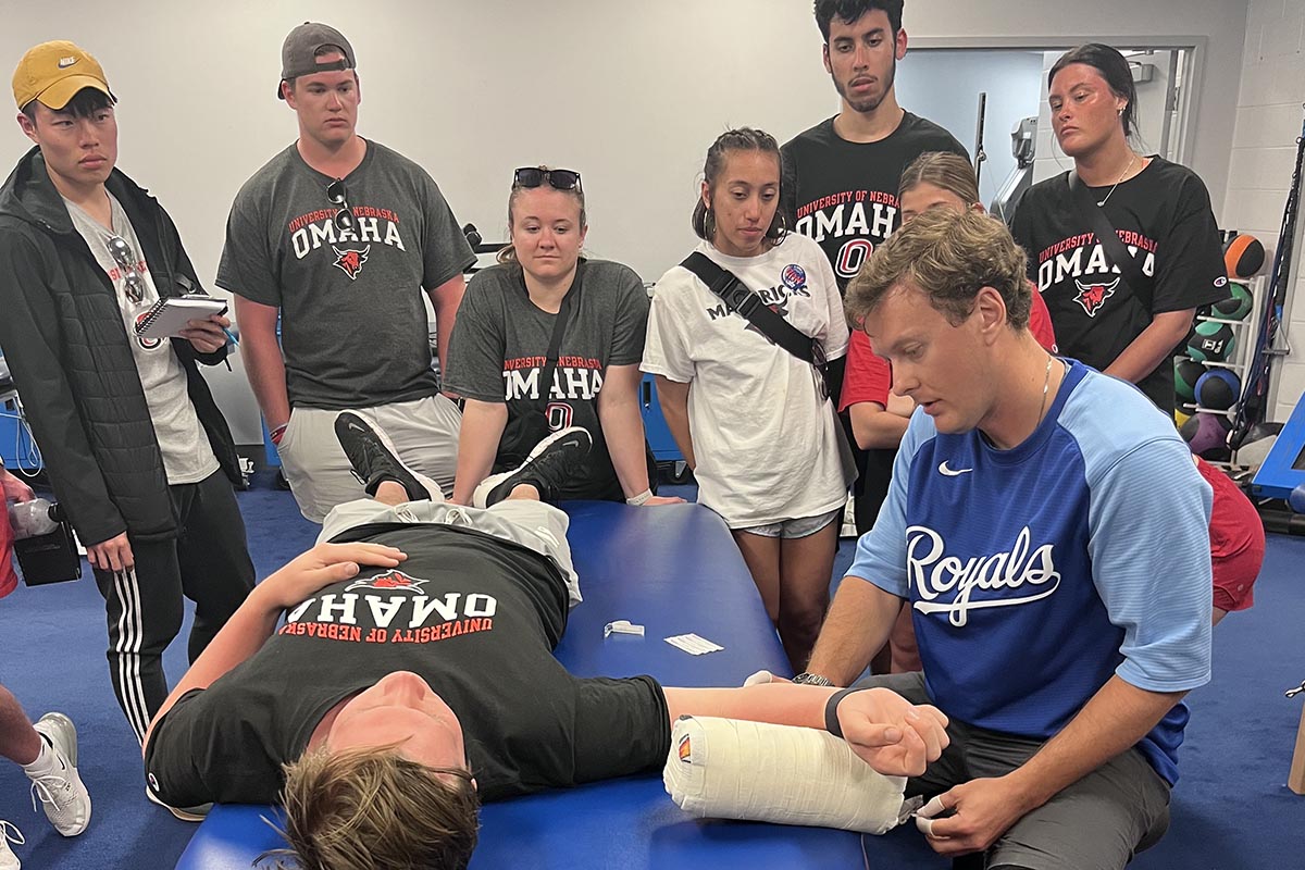A group of people watch a sports medicine demo.