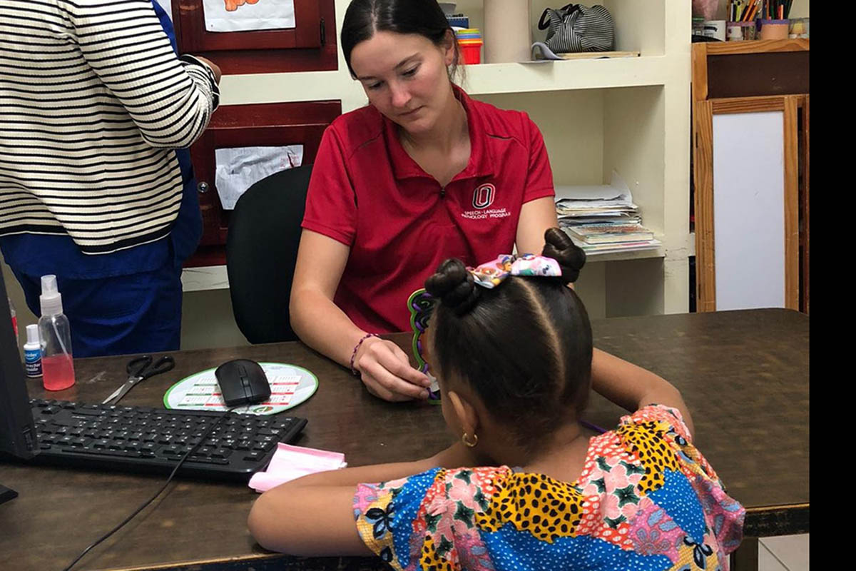 A student works with a child at a desk