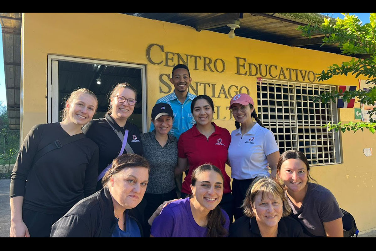 A group of people stand in front of a school