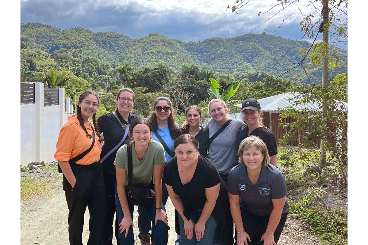 A group of people pose in front of beautiful tropical scenery of mountains and a blue sky