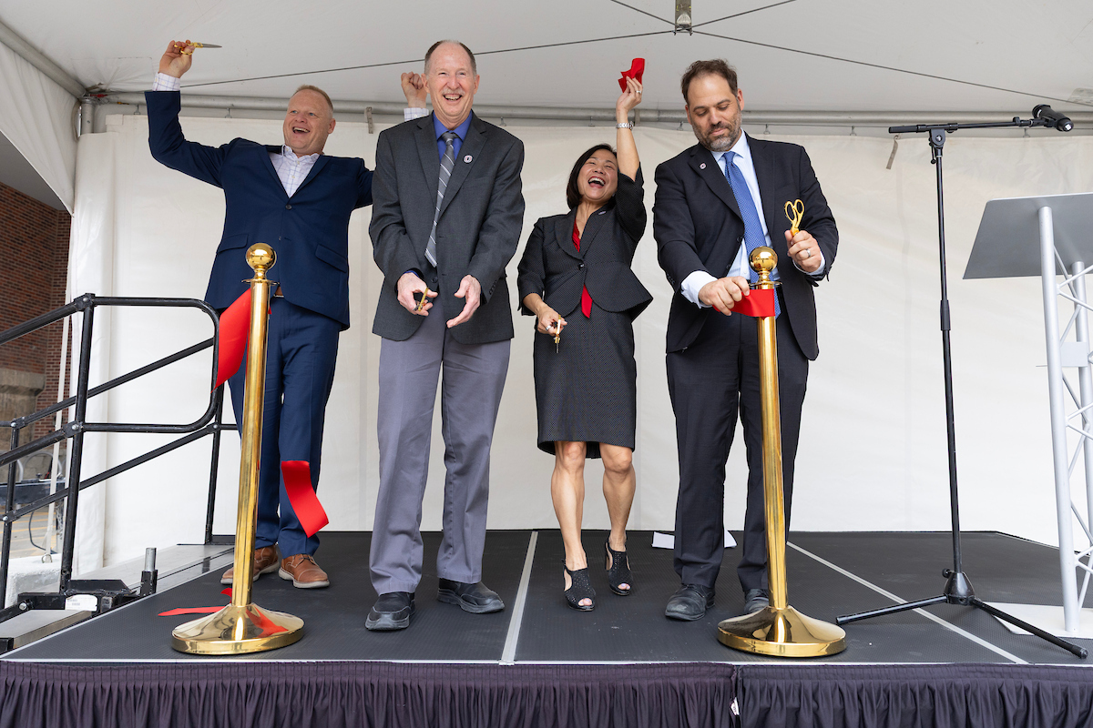 A group of people cheer and cut a ribbon during a grand opening