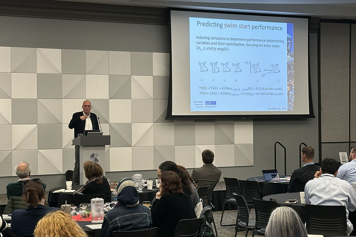 A professor presents research on a stage at a conference 