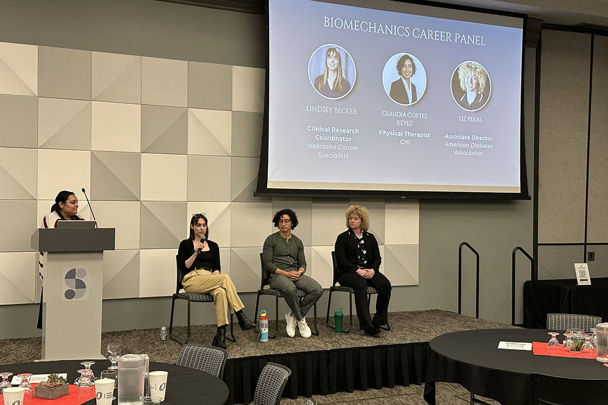 A panel discussion occurs on a stage at a conference