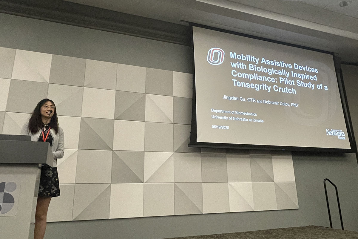 A student presents research on stage at a conference 