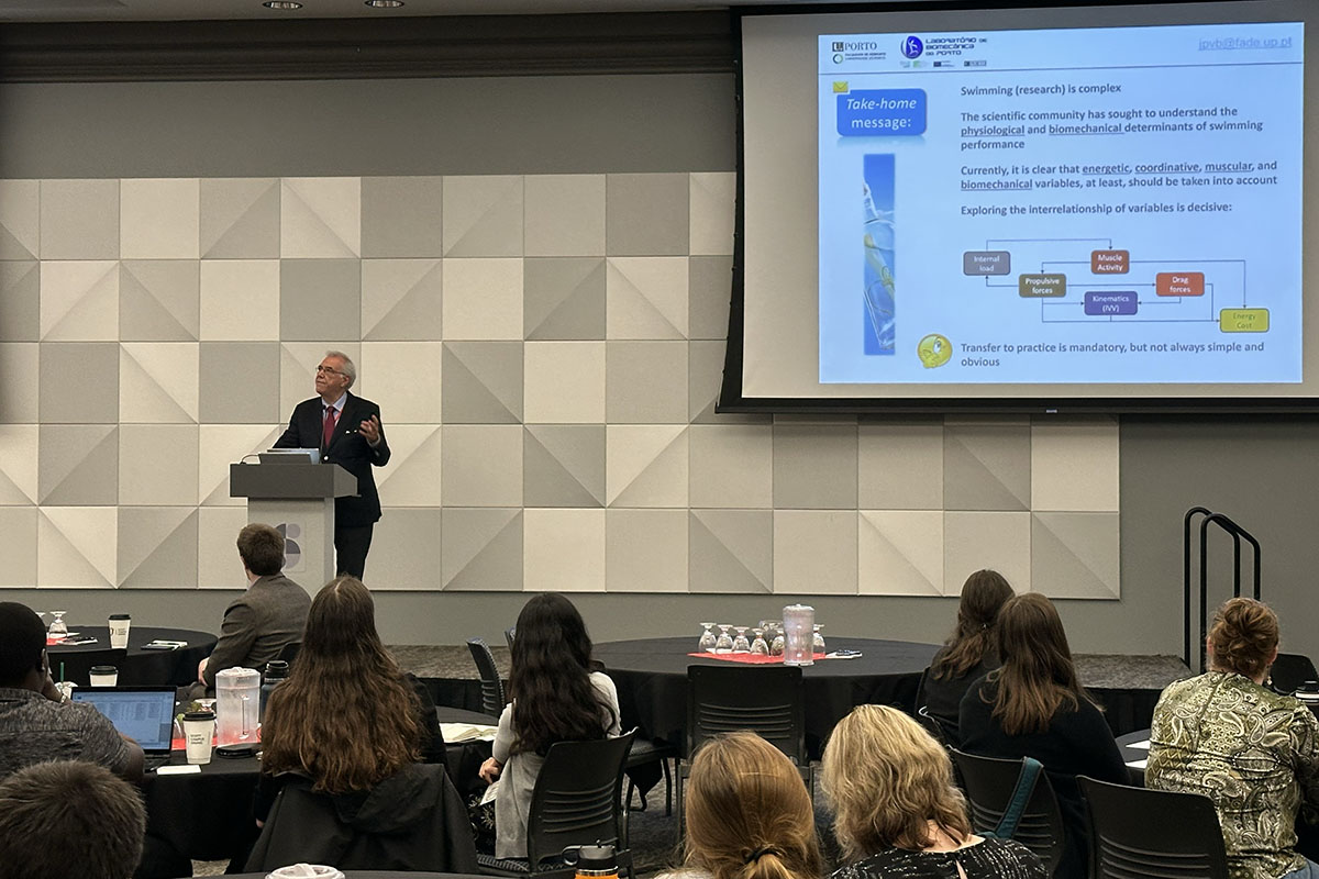 A professor presents research on a stage at a conference 