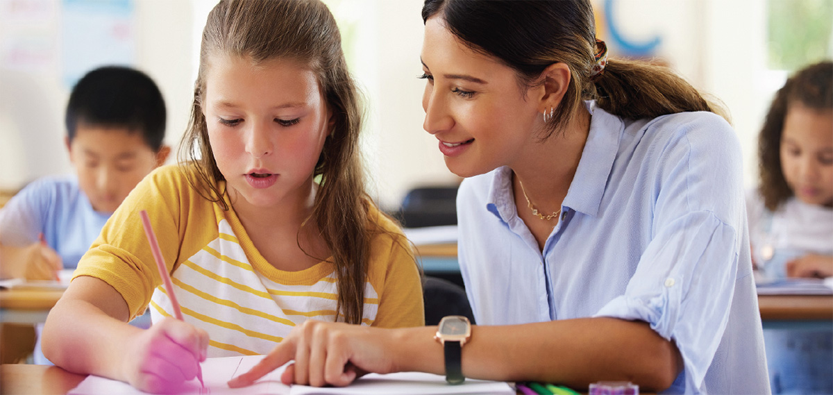 A teacher helps a child in a classroom