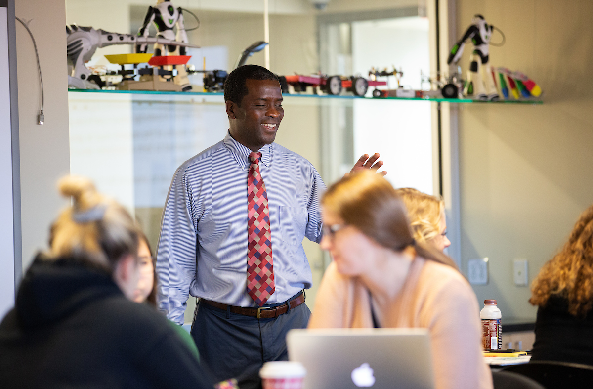 Dr. Derrick Nero stands in a classroom with students in the foreground