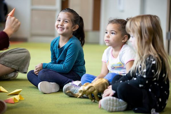 Three kids interact with a teacher at a childcare center