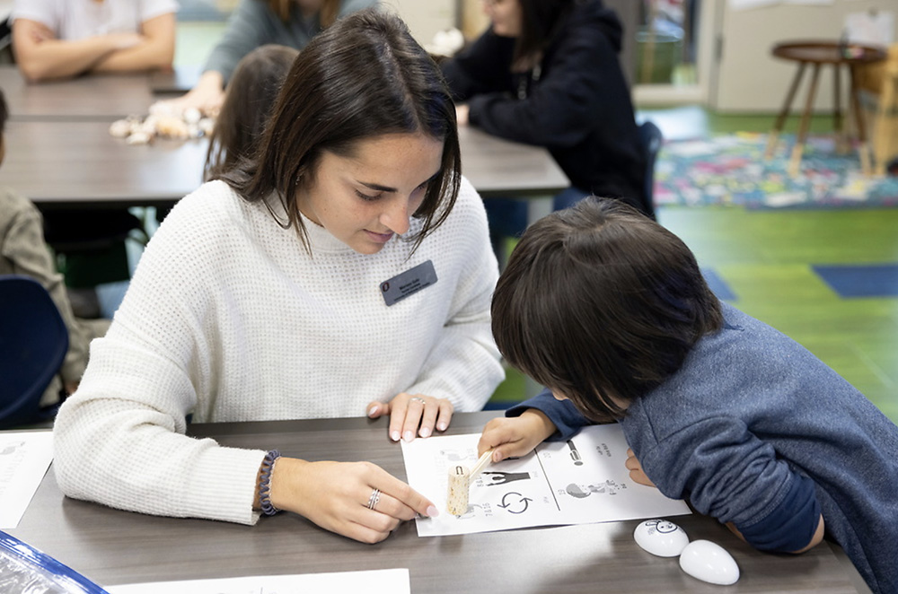 A teacher helps a child in a classroom