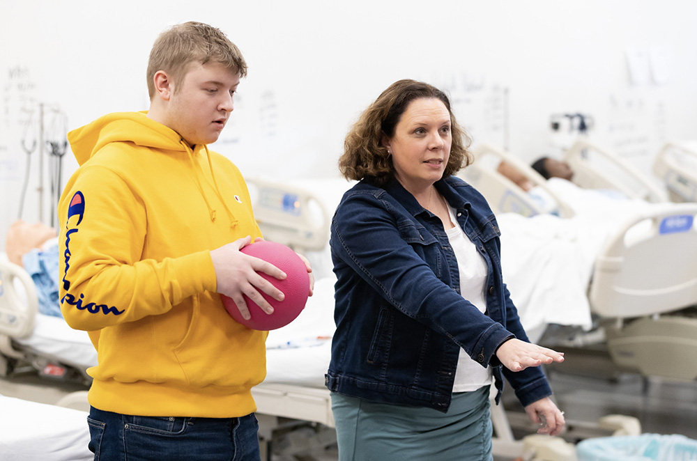 A high school teacher works with teens in a classroom