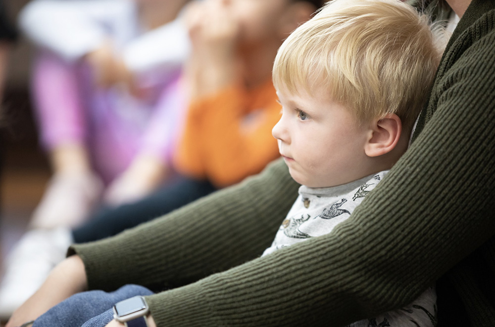 A child sits on a teachers lap in a childcare center