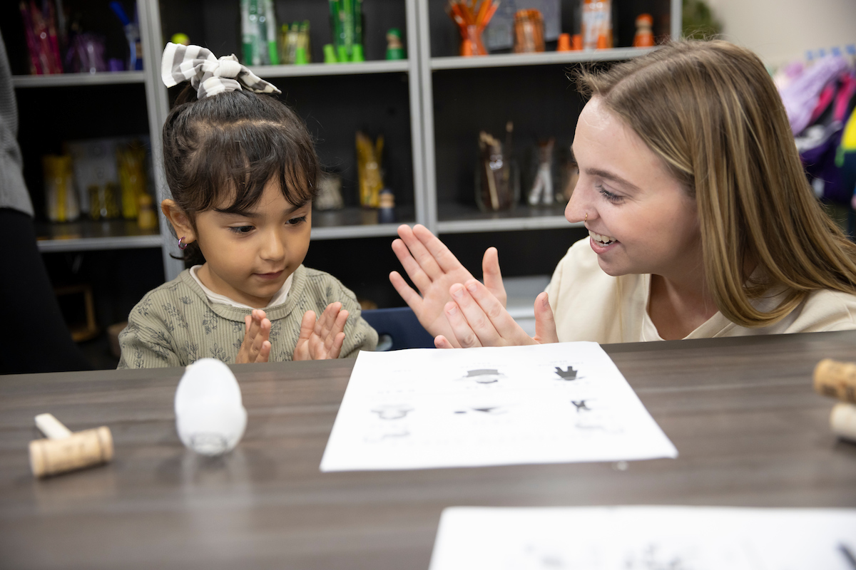 An aspiring educator works with a small child in a preschool