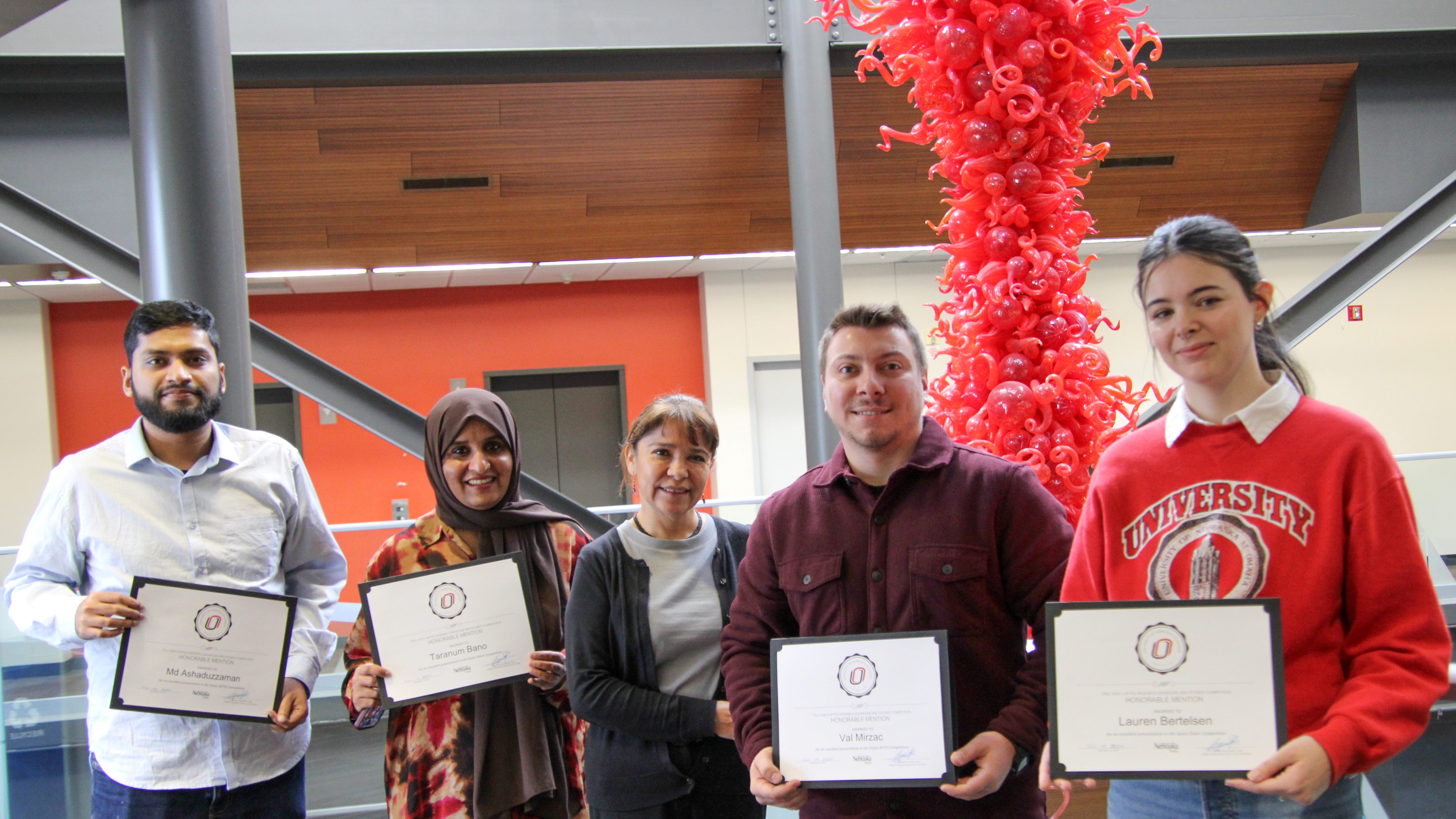 Students holding certificates at CBYTE event with red and orange decorations