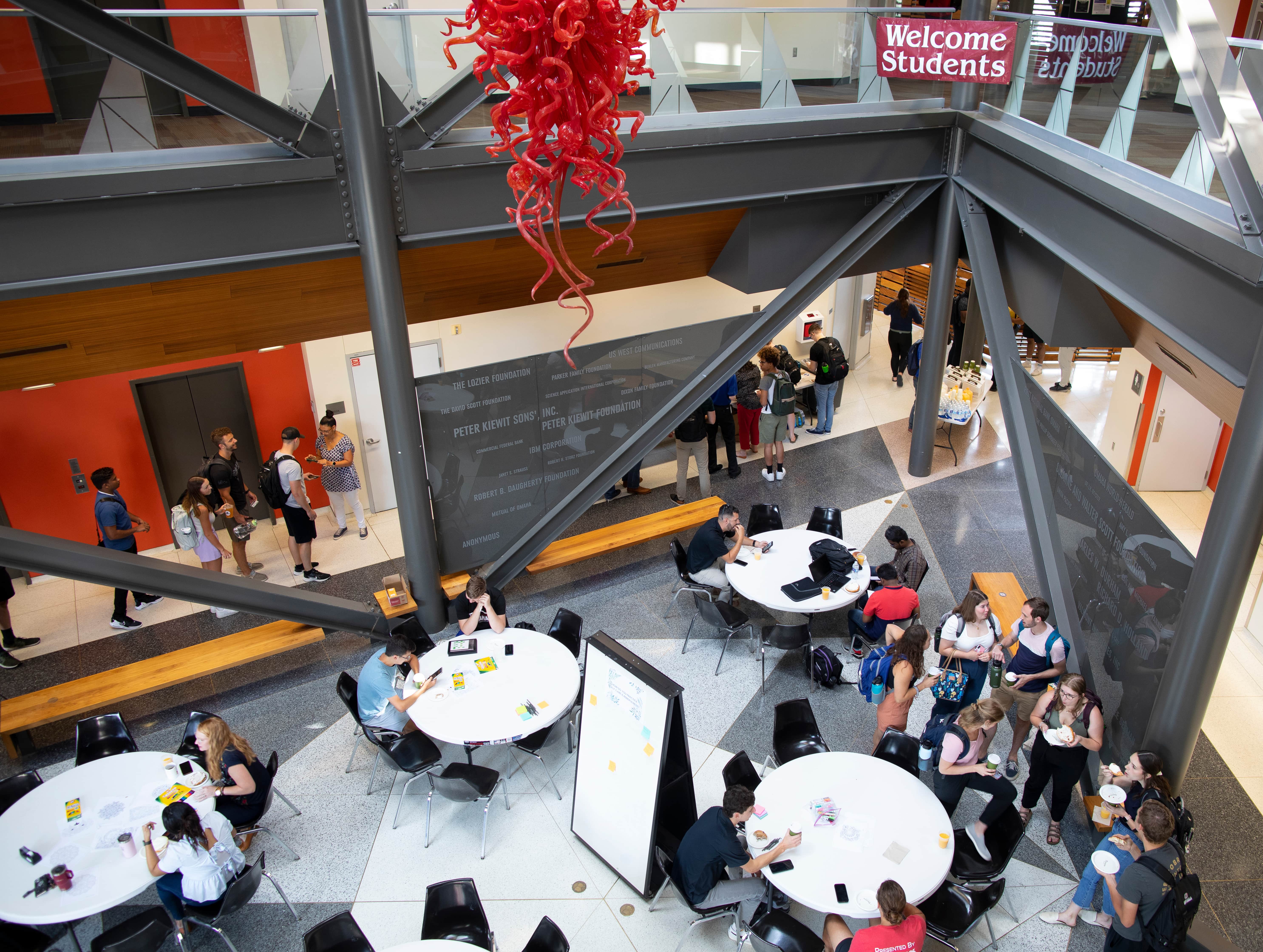 Aerial view of celebration event with students gathered at round tables in building atrium