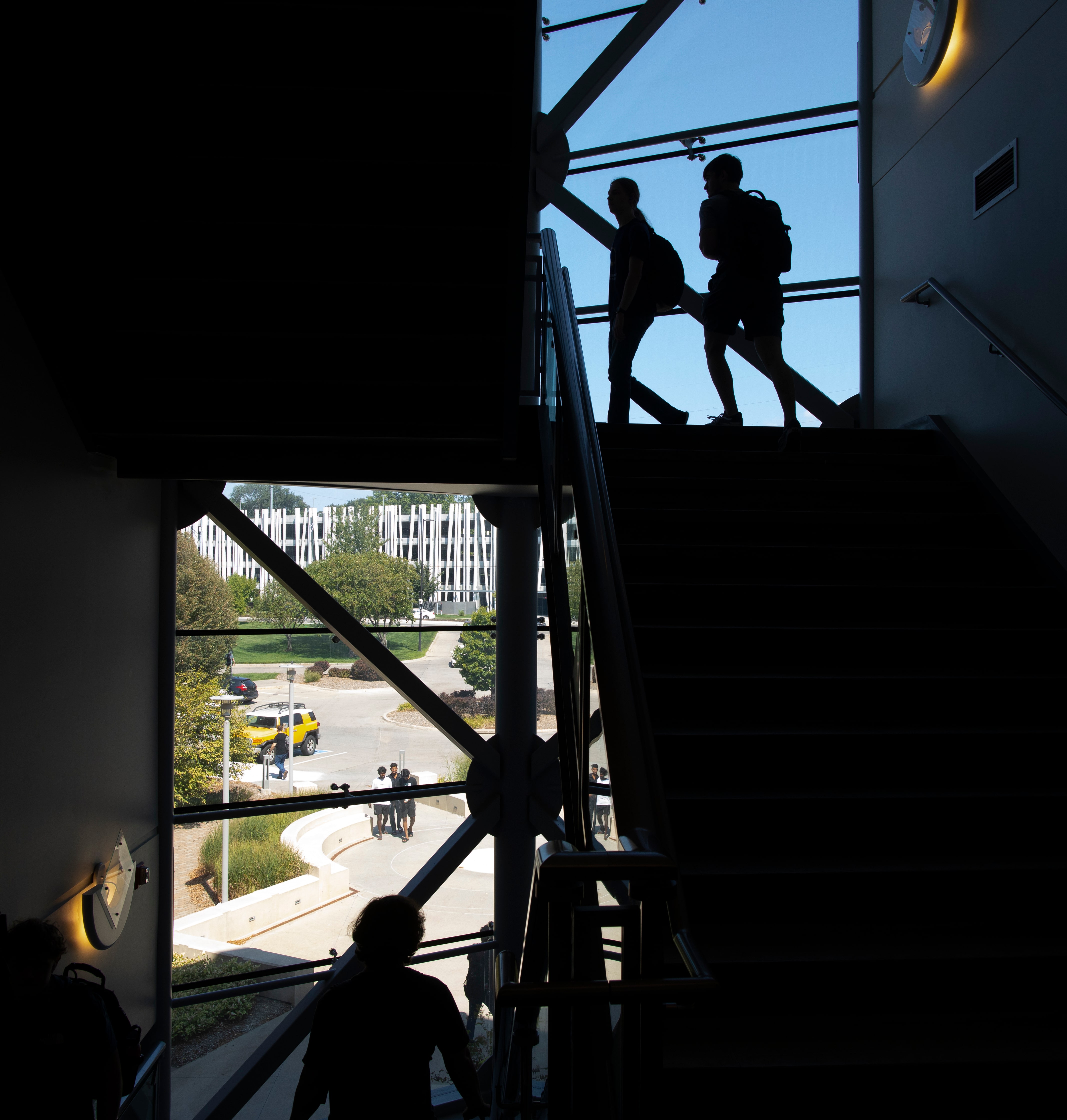 Silhouettes of people climbing metal framework structure against sky
