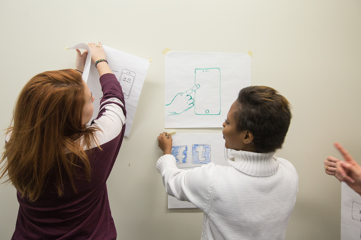 Two students working at a white board. 