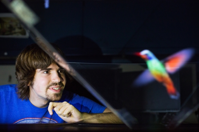 A man looking at a hologram hummingbird.