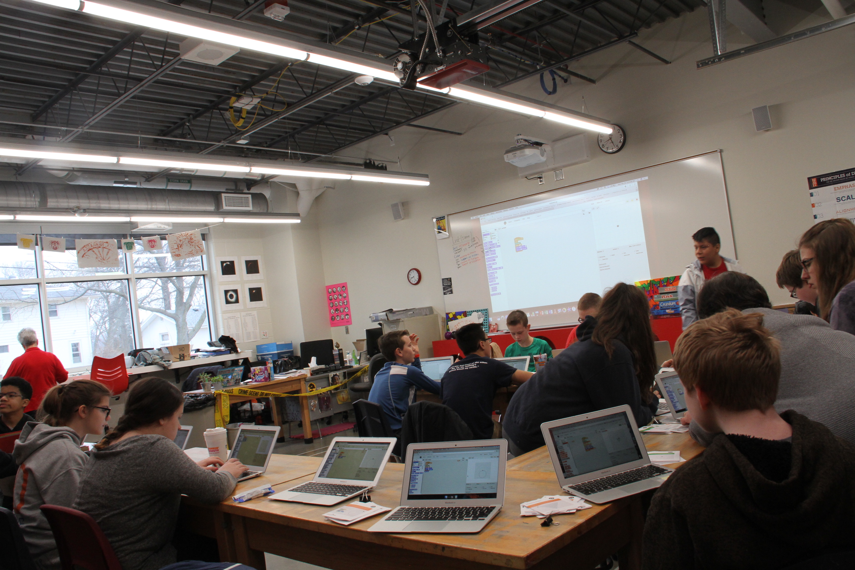 Students with laptops sit in a middle school room