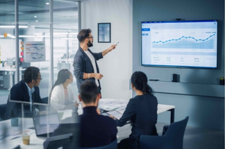 A group of people having a meeting to discuss business statistics on a projection.