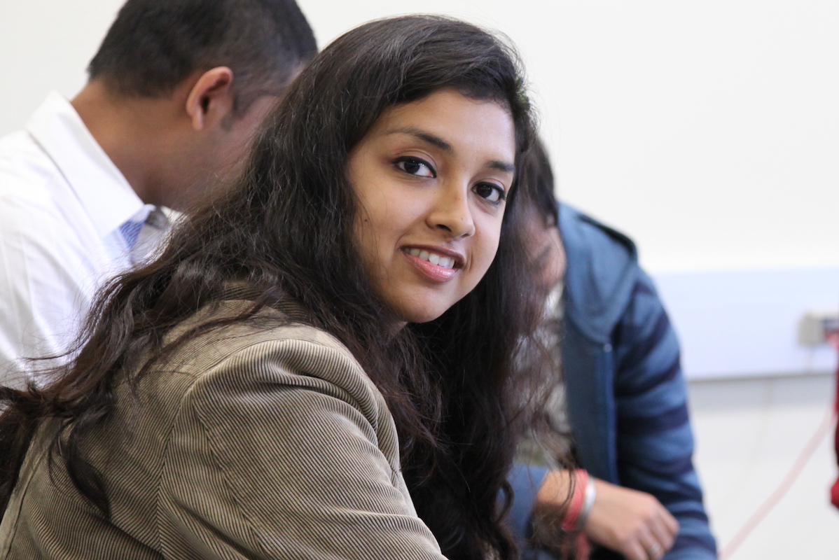 Student smiling with a small robot.