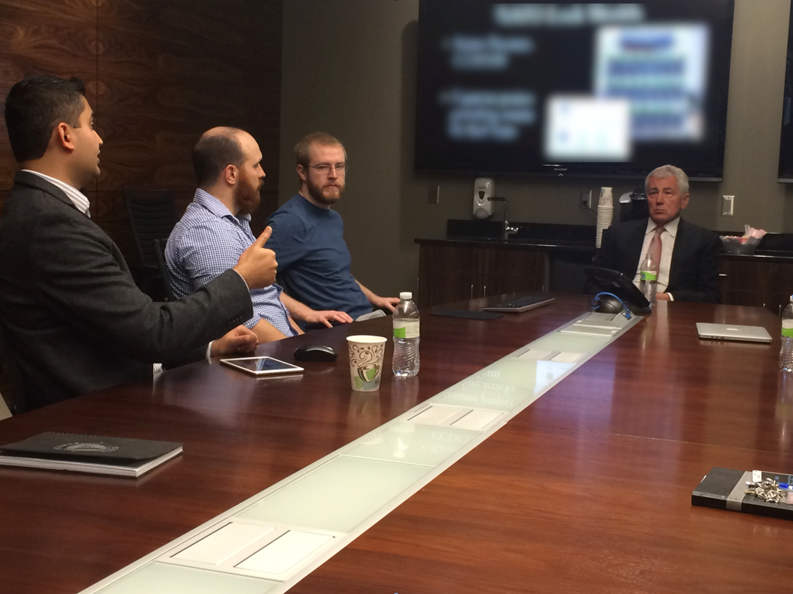 Faculty, students and Chuck Hagel sit around a conference table