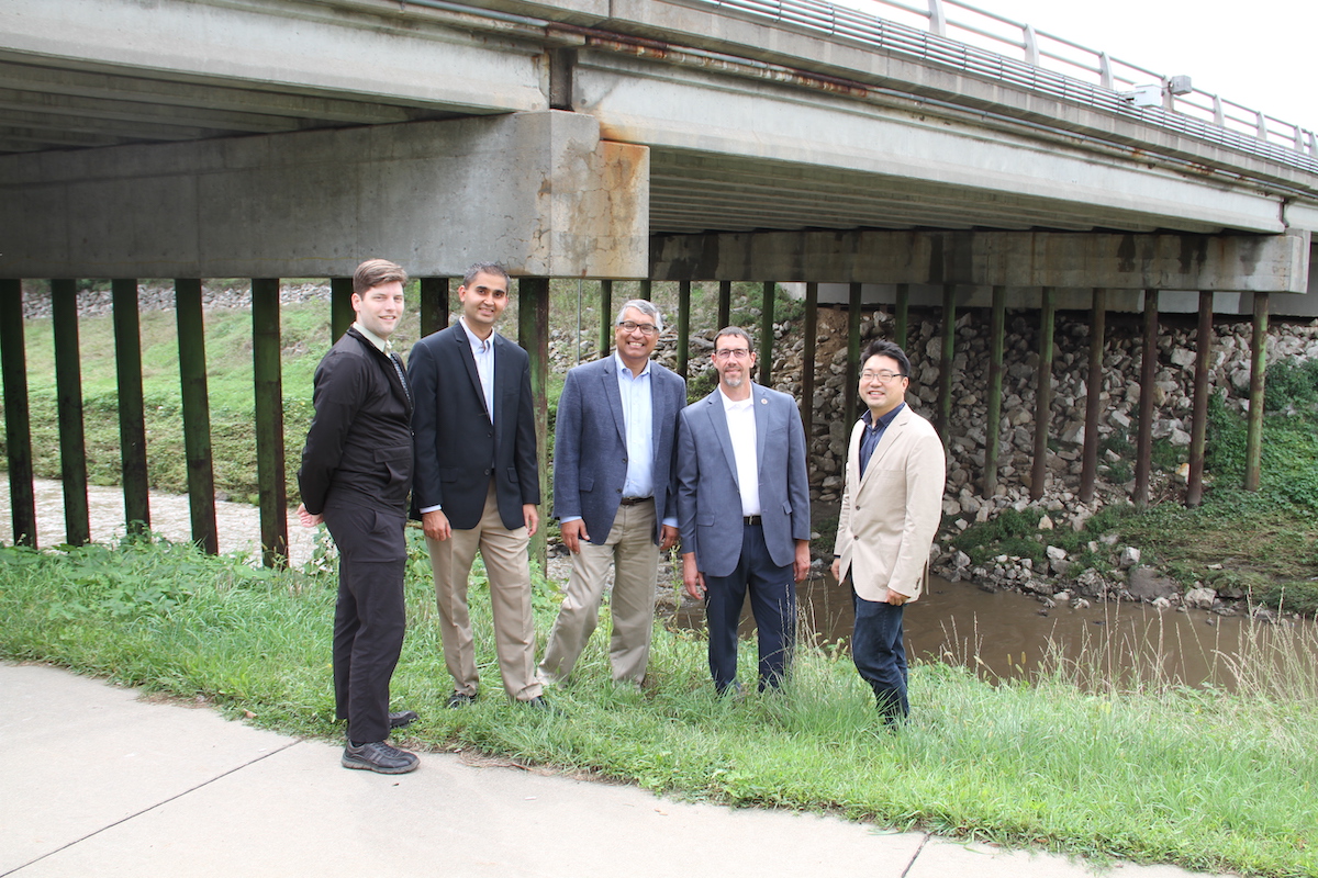 Professors standing under a bridge.