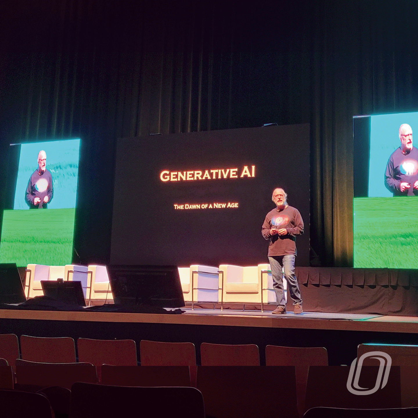 a male speaker standing on a stage in front of an audience with a large screen behind with a title "generative ai"