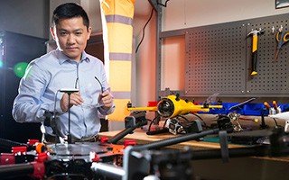 Student standing in room with a few flight drones