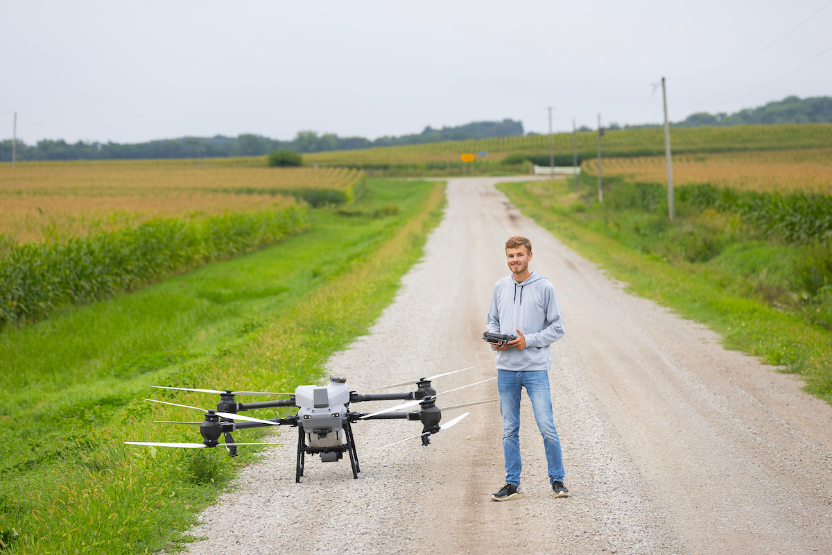 Student pictured with a drone in a field. 