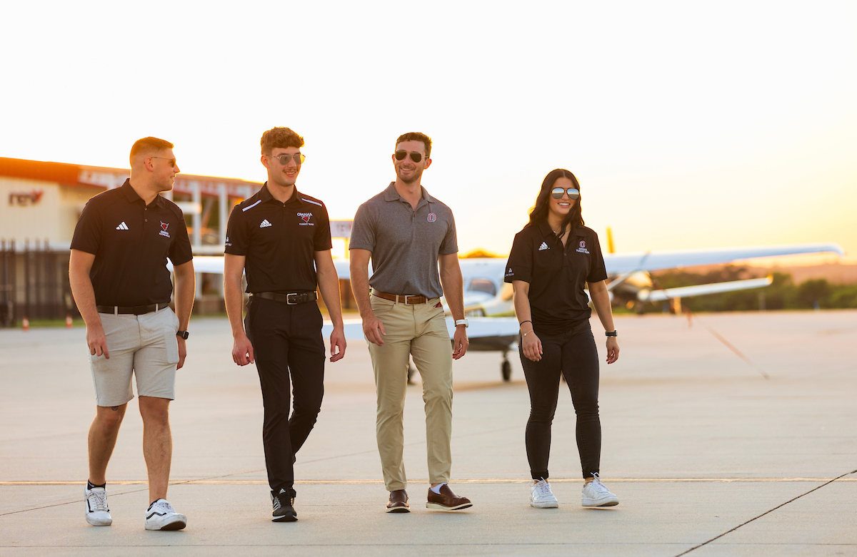 Four students walking on tarmac.