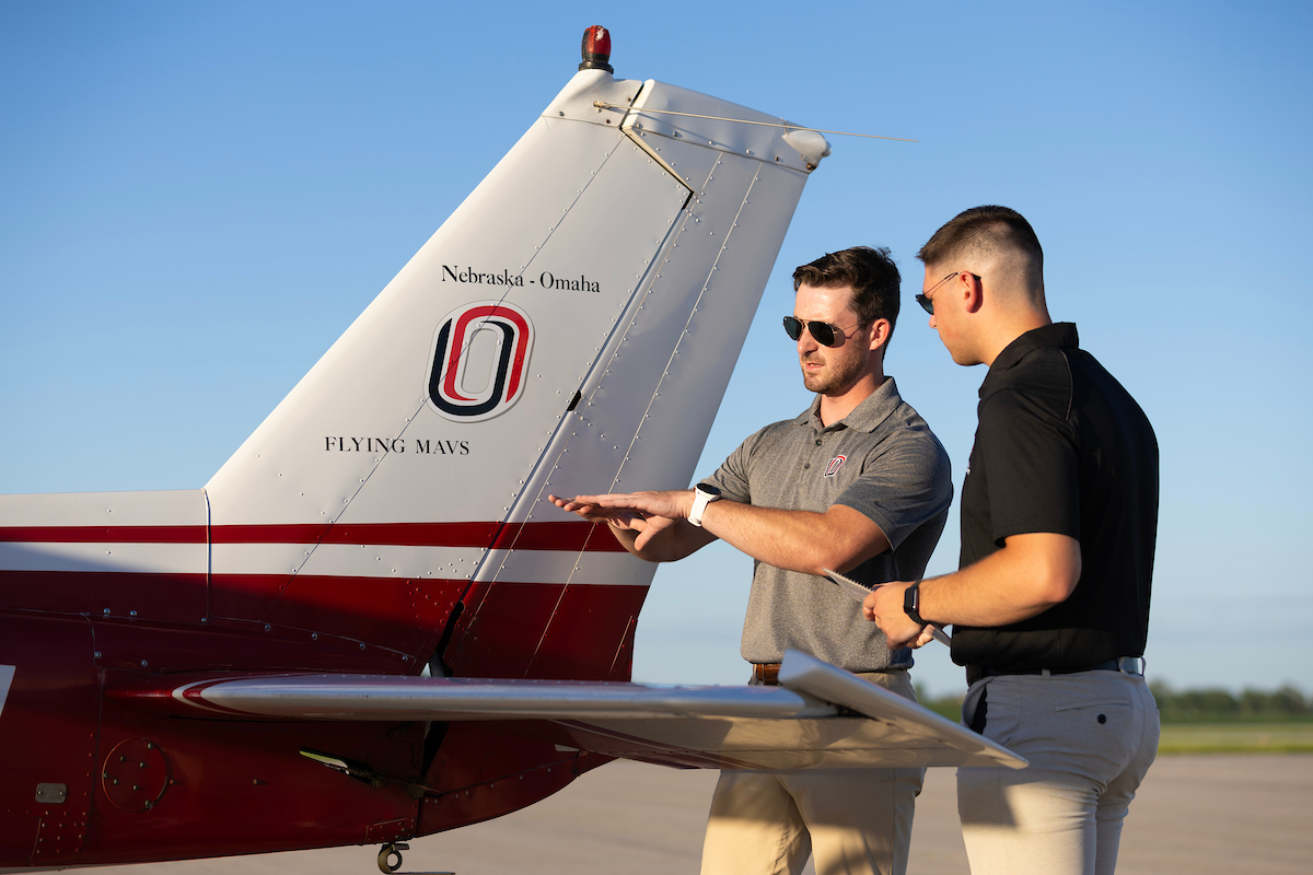 Two students posed in front of an airplane.