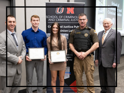 Students holding a certificate next to a police officer.