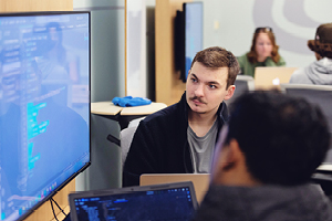 Two men looking at code on a computer screen.