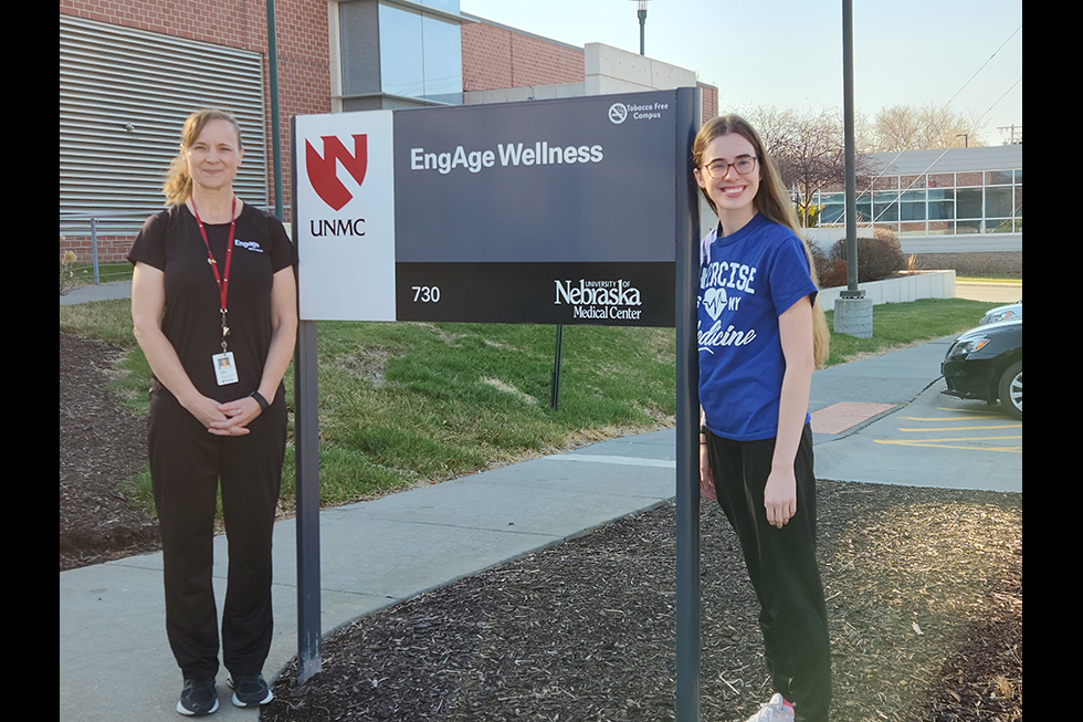 Two women standing by the Engage wellness sign outside