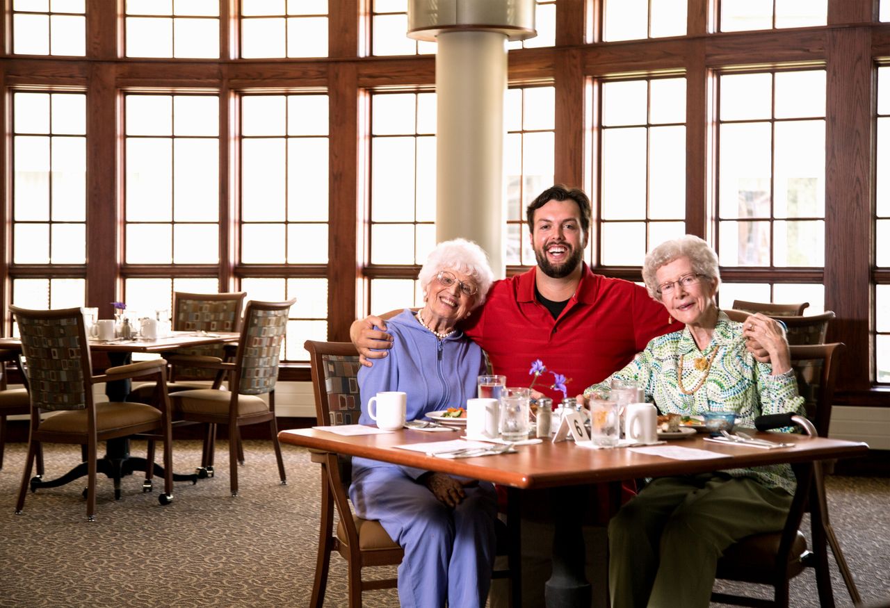 Male student seated with two older women in dining room
