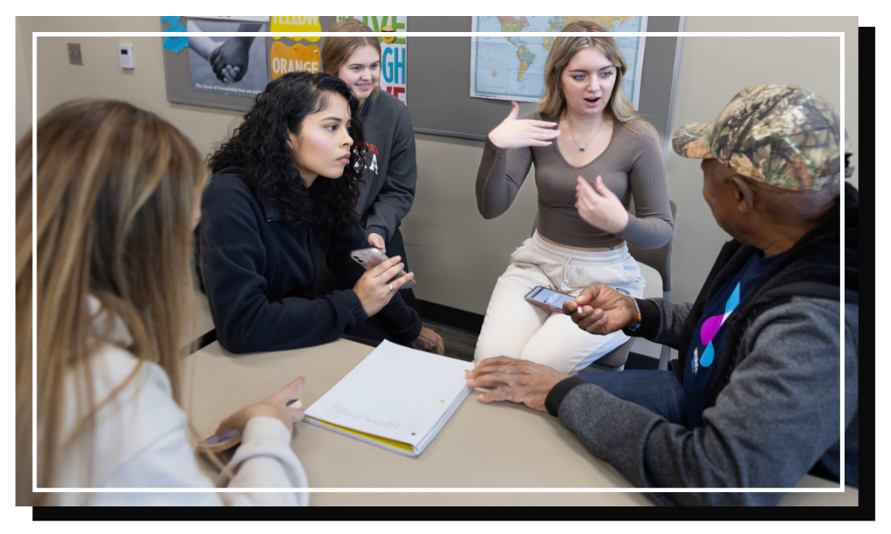 three students playing foosball with a senior.