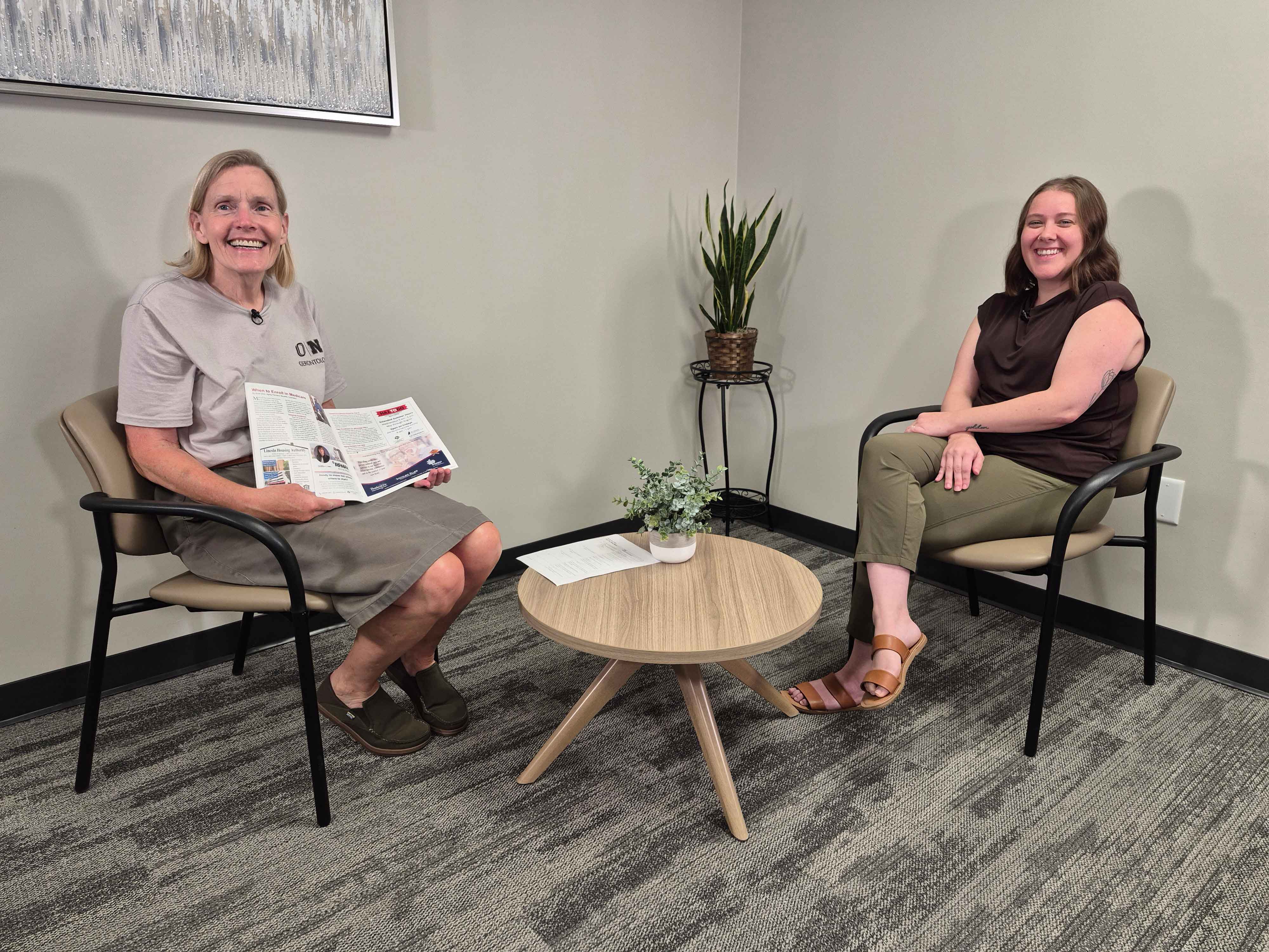 Julie Masters and Molli Stolz, Aging Partners Benefits Specialist, sitting across from one another separated by small table in a room. 
