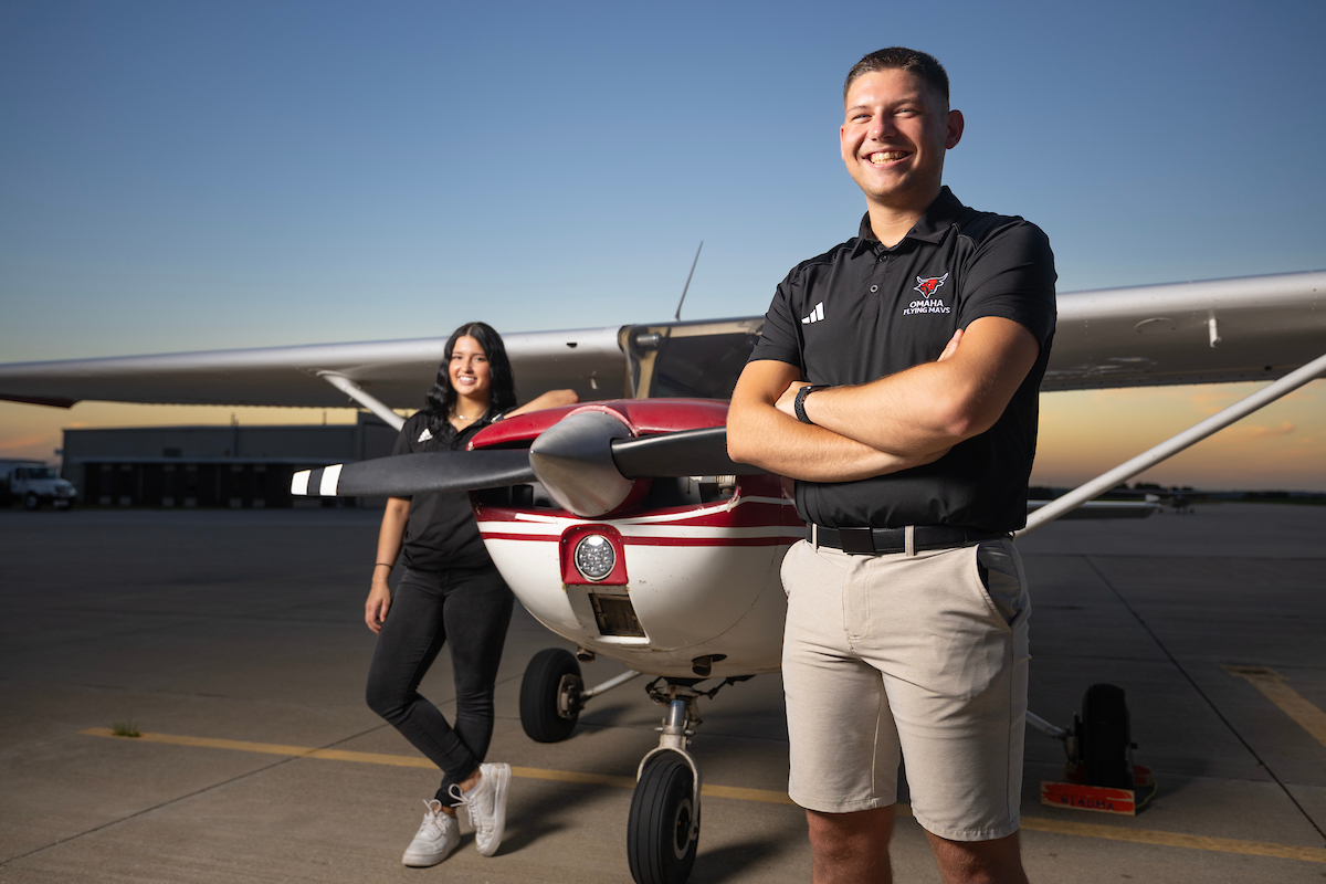 two students standing near an airplane