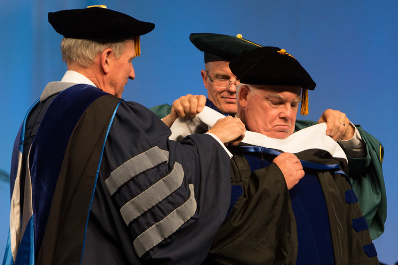 Dean Bartle is hooded by Binghamton University Provost Don Nieman and President Harvey Stenger. Image courtesy: Jonathan Cohen/Binghamton University.