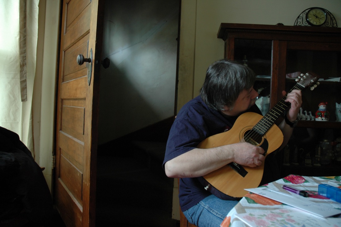 Szto photograph of man playing guitar.