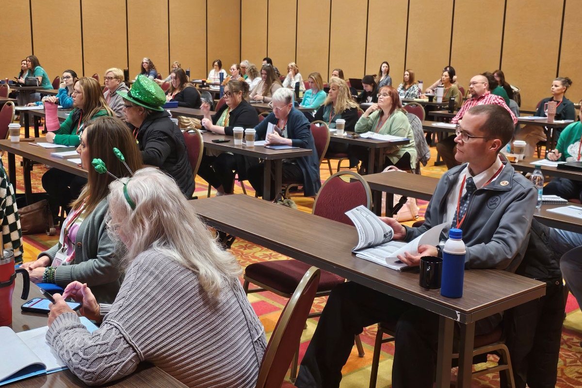 Clerks sitting at tables in a classroom setting.