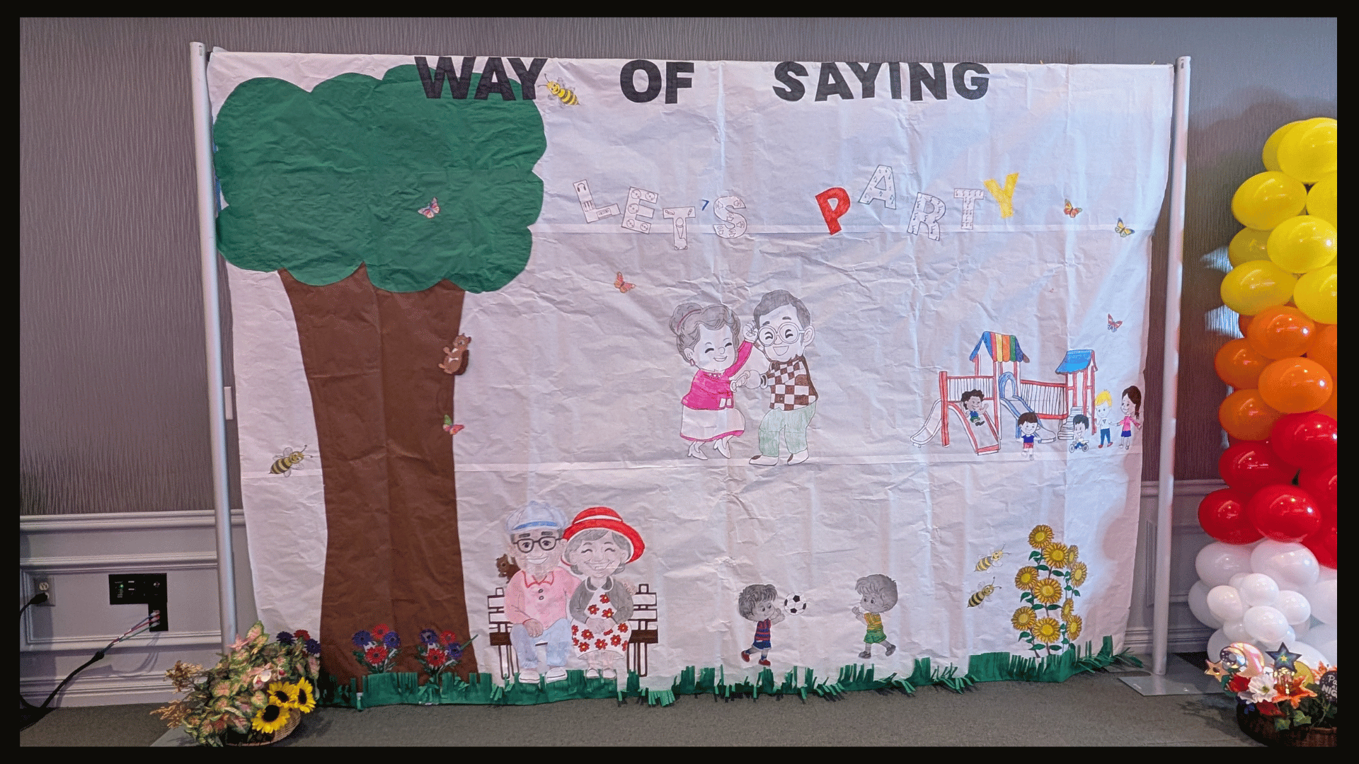 Wall size paper banner with hand-drawn people, flowers, and trees.